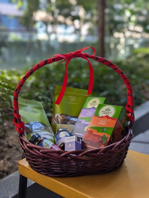 Teas, supplements, snacks and essential oil in a basket shot with a green background